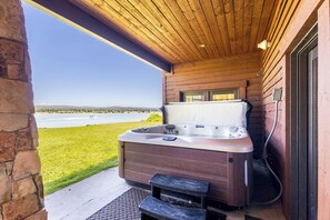 A hot tub in a covered outdoor area with a view of a lake. - Sandy Beach Lodge | Lakefront Luxury | 30min to YNP (Island Park)