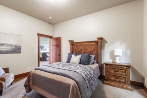 A bedroom with a bed, bedside table, and a door leading to another room. - Sandy Beach Lodge | Lakefront Luxury | 30min to YNP (Island Park)