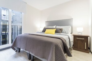 Un dormitorio moderno con una cama grande, una mesita de noche y vistas al exterior.