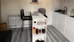 Pieni, käytännöllinen keittiö, jossa on ruokapöytä, tuolit, valkoinen kaappi ja patteri.