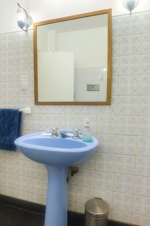 A bathroom with a blue sink, a mirror, and patterned tiles. - Vrbo Property (Martínez)