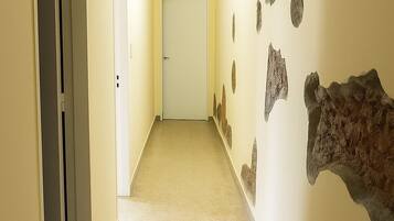 A hallway with beige walls, a carpeted floor, and a door at the end.