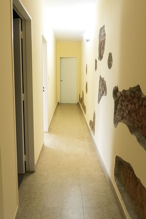 A hallway with beige walls, a carpeted floor, and a door at the end.