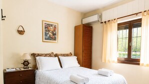 Une chambre à coucher comprenant un lit, une table de chevet, une armoire, une fenêtre avec des rideaux et un luminaire suspendu.