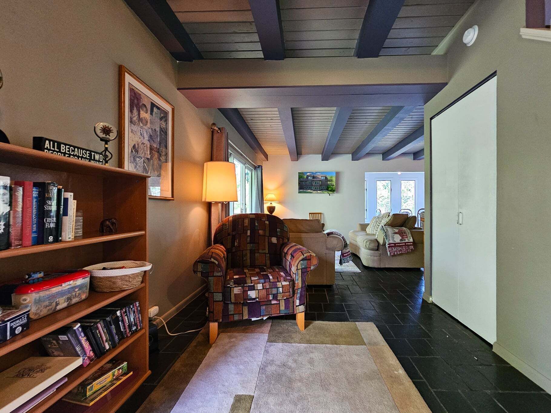 Una sala de estar acogedora con una estantería, un sillón estampado y un sofá.