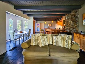 Una sala acogedora con sofá, una mesa de comedor y sillas, una cocina con armarios de madera y una pared de acento de piedra.