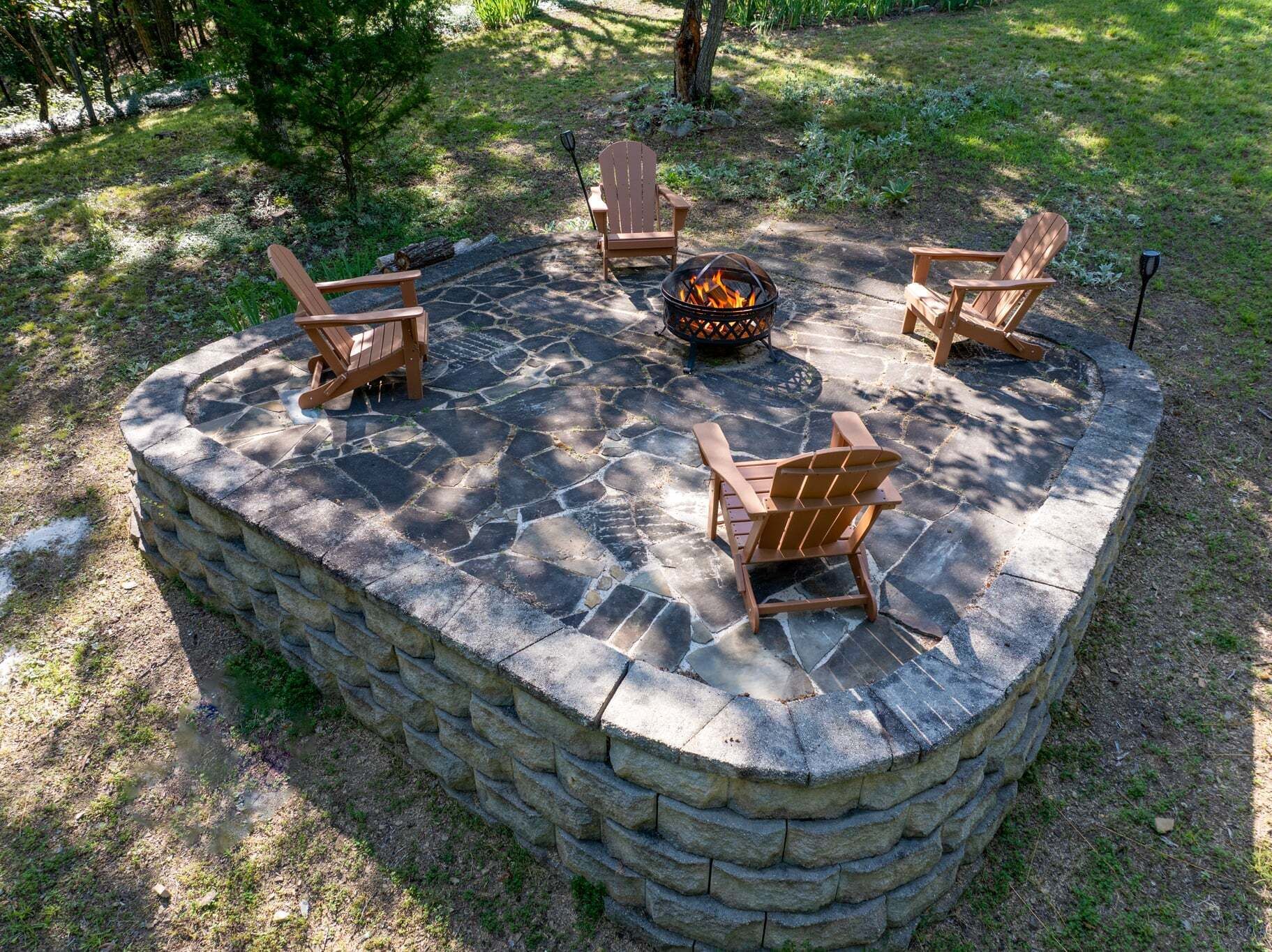 Un hogar de piedra rodeado de cuatro sillas Adirondack.