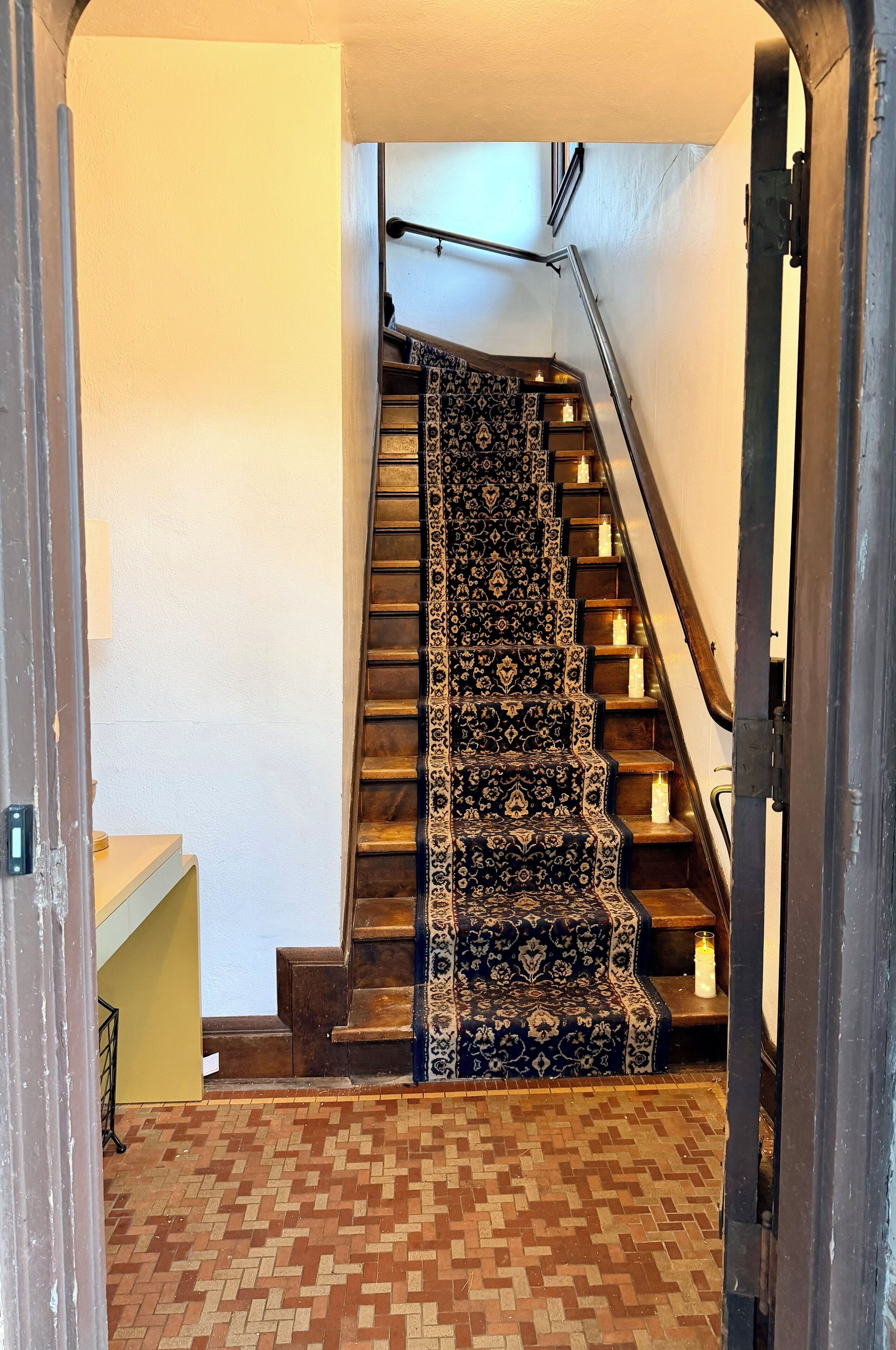 A staircase with a patterned carpet and candles on each step.