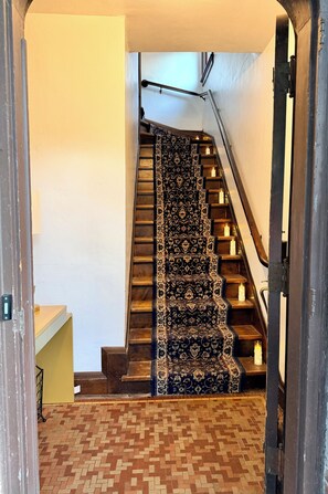 Una escalera con alfombra estampada y velas en cada peldaño.