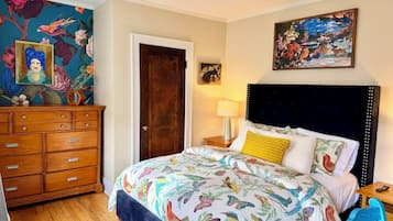 A bedroom with a bed, dresser, and a door.
