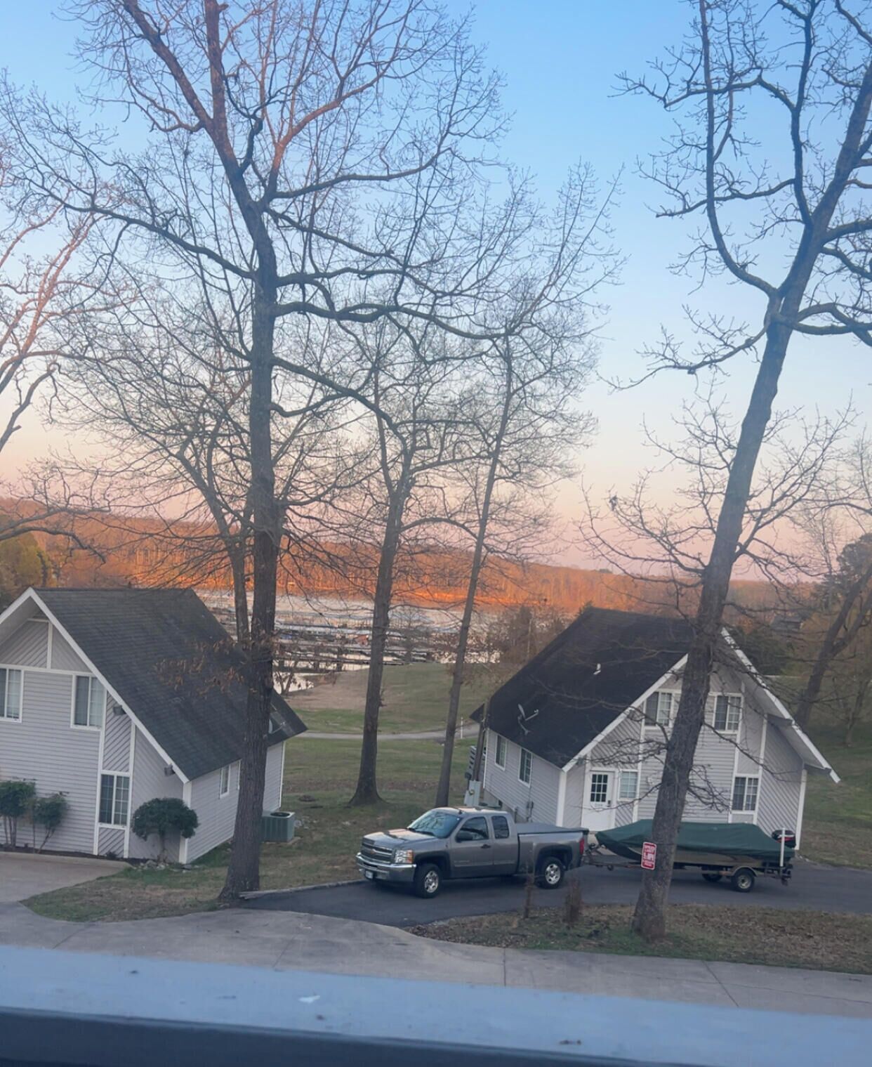 A residential area with two houses, a parked truck, and leafless trees.