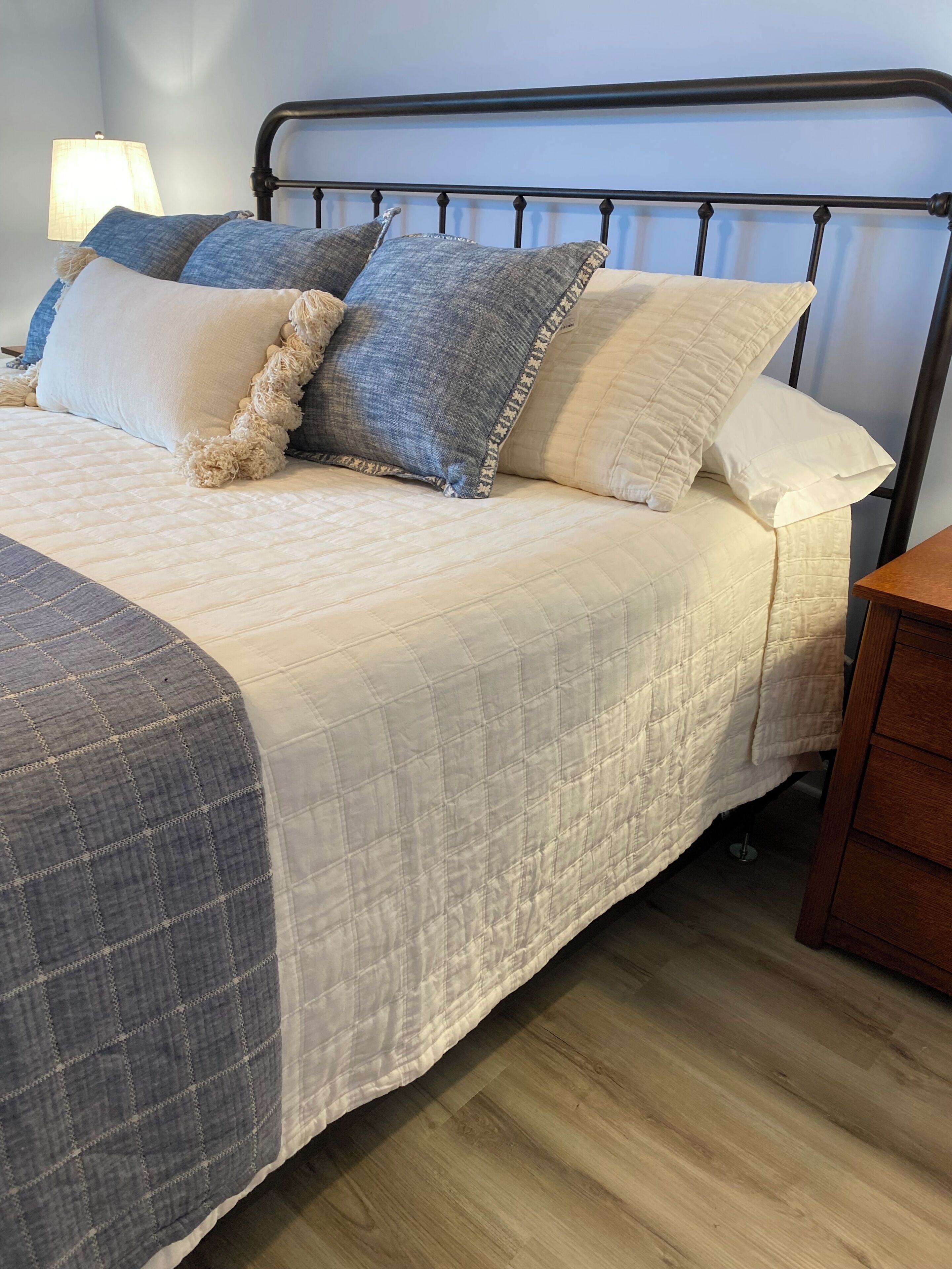 A bed with a quilted headboard, a bedside table, and a lamp.