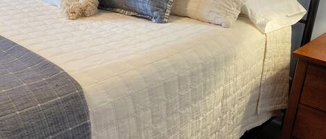 A bed with a quilted headboard, a bedside table, and a lamp.