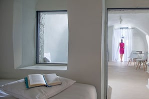 A bedroom with a window, a bed, and an open book. - Auralyth Suite, Divine Sea Views, Outdoor Private Pool, Furnished Terrace,. (Santorini)