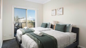 Ein Schlafzimmer mit zwei Betten, einem Fenster mit Blick und zwei an der Wand befestigten Kunstwerken.