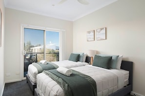 Ein Schlafzimmer mit zwei Betten, einem Fenster mit Blick und zwei an der Wand befestigten Kunstwerken.