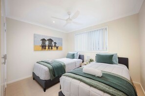A hotel room with two beds, a ceiling fan, a painting on the wall, and a window with blinds. - Oceans 2, Ocean Views, 3-Min Walk to Birubi Beach (Anna Bay)