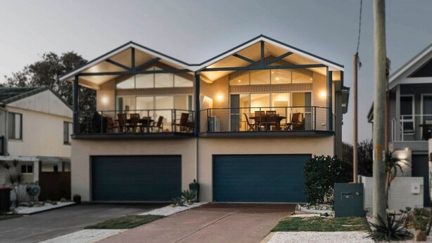 Ein zweistöckiges Haus mit Balkon, Garage und gepflegtem Rasen.