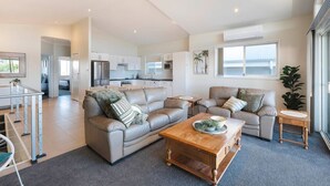 Ein modernes Wohnzimmer mit einer Couch, einem Couchtisch und einem Essbereich mit Stühlen.