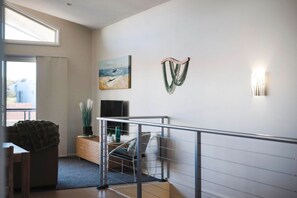 A modern interior with a staircase, a flat-screen TV, and a painting on the wall. - Oceans 2, Ocean Views, 3-Min Walk to Birubi Beach (Anna Bay)