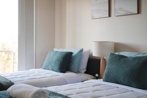 A hotel room with two beds, a bedside table with a lamp, and a window with curtains. - Oceans 2, Ocean Views, 3-Min Walk to Birubi Beach (Anna Bay)
