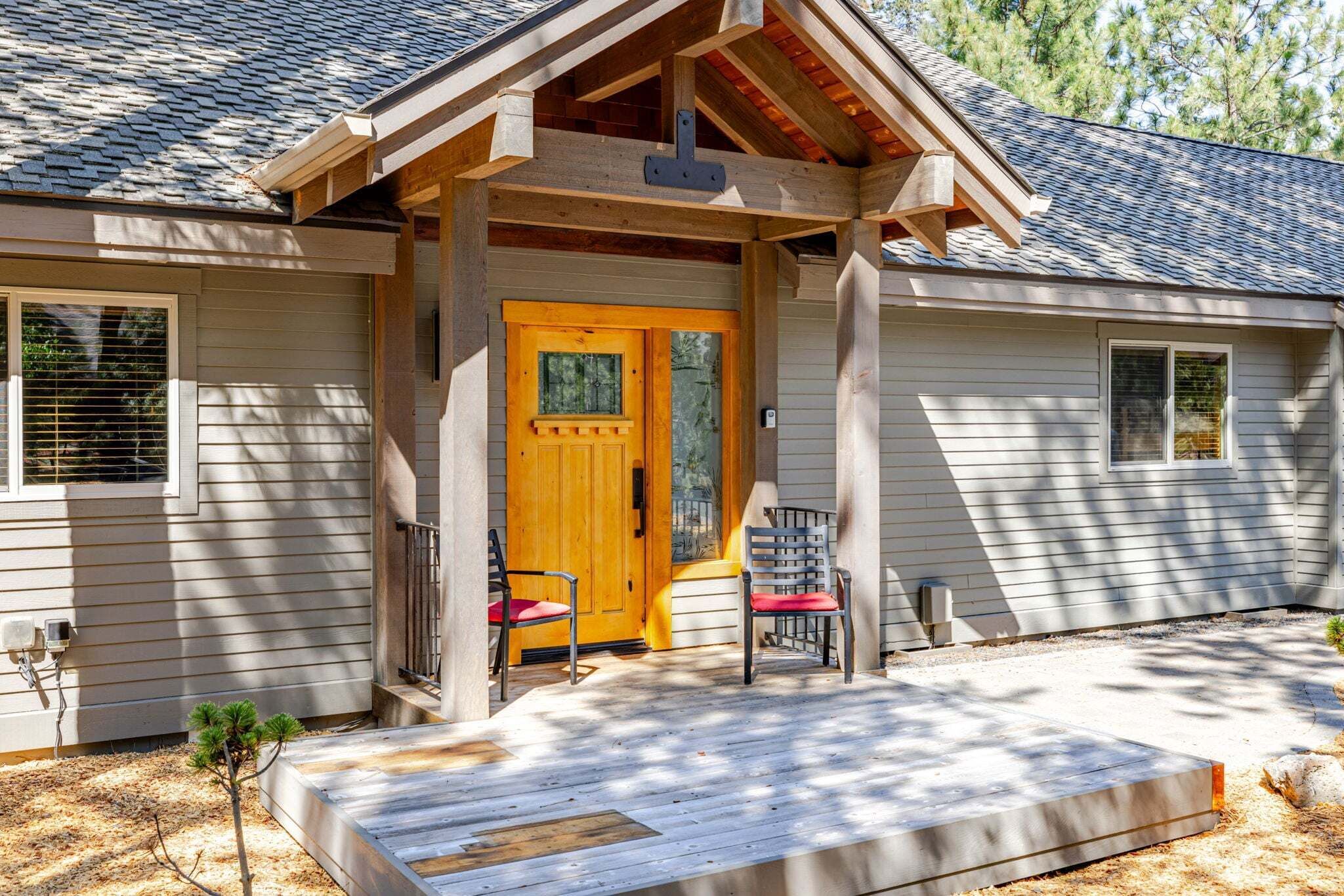 A house with a wooden front porch, a door, and two chairs.