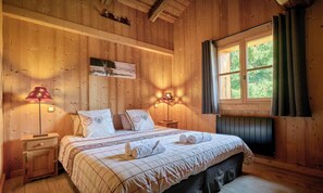 A wooden room with a bed, two bedside tables, a window with curtains, and wall-mounted lamps. - Ferme de Chry - Former farmhouse with traditional charm - OVO Network (Les Gets)