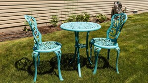 A small outdoor seating area with two chairs and a table, surrounded by a grassy lawn and a wooden fence. - Sunshine House | Bright & Cozy Getaway for Families, Friends, and Relaxation (Rexburg)