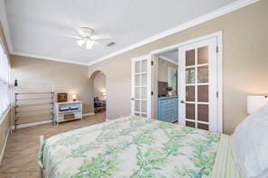 A bedroom with a bed, a ceiling fan, a wardrobe, a desk, and a door leading to another room. - 👣Barefoot Beach Resort #E211 - 2 Bedroom condo in Indian Shores Beach with a Pool!🩴 (Indian Shores)
