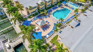 Una vista aerea di un resort con piscina, lettini e palme.