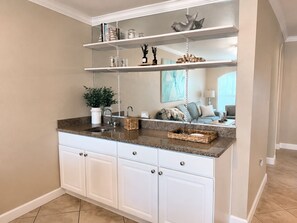 Eine Küche mit weißen Schränken, Granit Arbeitsplatten und einem hängenden Regal über dem Spülbecken.