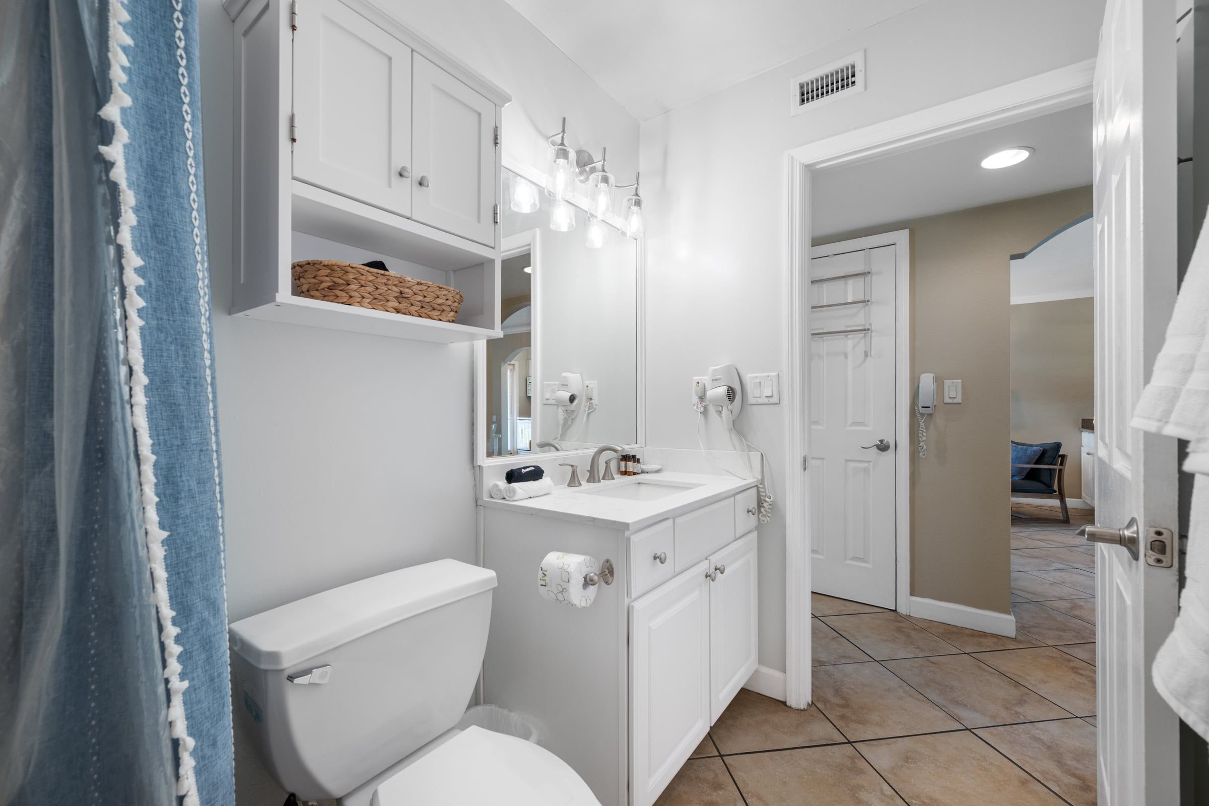 A bathroom with a toilet, sink, mirror, and towel rack.