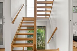 A wooden staircase with a glass door leading to a balcony. - Alex Headland Haven - 3 Level Modern Retreat (Mooloolaba Region)