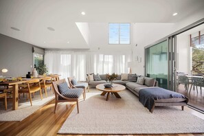 A modern living room with a dining area, a sofa set, and a coffee table. - Alex Headland Haven - 3 Level Modern Retreat (Mooloolaba Region)