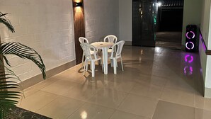 Ein Zimmer mit Esstisch und Stühlen, einer Wandleuchte und einer Tür zu einem weiteren Bereich.