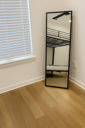 Una habitación con literas, un espejo grande y una ventana con persianas.