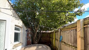 A backyard with a hot tub, a wooden fence, and a tree providing shade. - Peaceful Hot Tub Hideaway w/Private Garden (Cardiff)