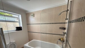 A modern bathroom with a bathtub, two toilets, a shower, and a window with a view of greenery. - Peaceful Hot Tub Hideaway w/Private Garden (Cardiff)