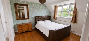 Ein Schlafzimmer mit einem Bett, einem Schminktisch, einem Fenster und einem Spiegel.