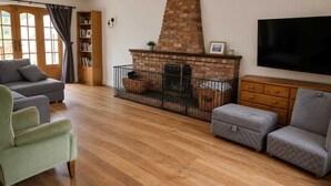 A living room with a fireplace, a television, and a bookshelf. - Spacious Detached 4-Bedroom Family Home with Large Garden (Worminghall)