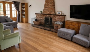 A living room with a fireplace, a television, and a bookshelf. - Spacious Detached 4-Bedroom Family Home with Large Garden (Worminghall)