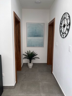 En hall med en krukväxt, en klocka och en tavla på väggen.