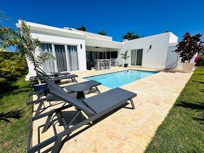 Una casa moderna amb piscina, mobles d'exterior i un jardí ben cuidat.