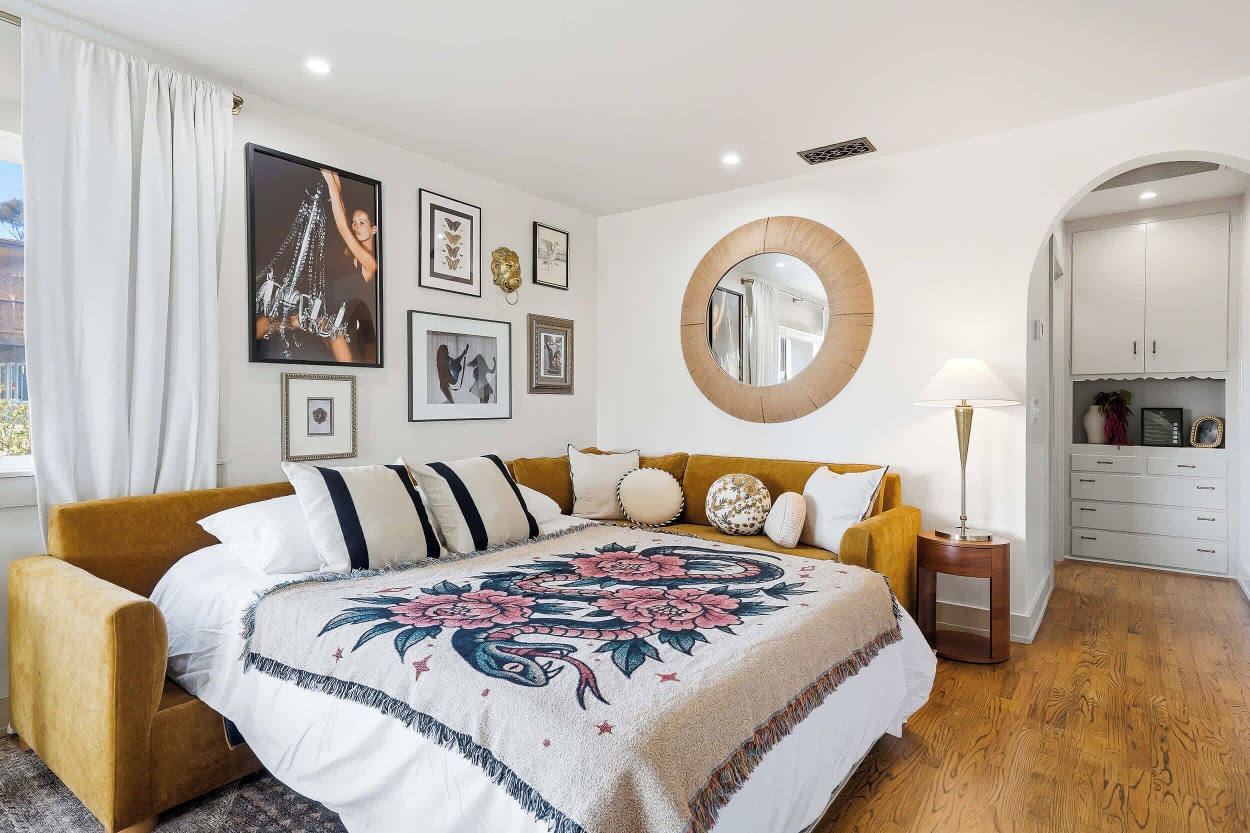 A bedroom with a bed, a round mirror, a nightstand, and a wardrobe.