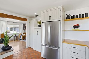 Una cocina moderna con refrigerador de acero inoxidable, armarios blancos y encimera de madera.