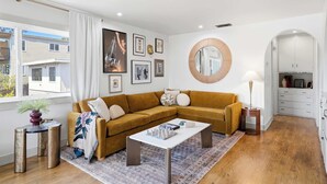 Ein modernes Wohnzimmer mit einer Eckcouch, einem Couchtisch und einem runden Spiegel.