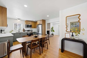A modern kitchen with wooden cabinets, stainless steel appliances, and a dining area with a wooden table and chairs. - Family Oasis! Hot Tub Fire Pit Game Room Sleeps 12 (San Diego)