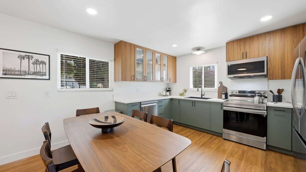 A modern kitchen with wooden cabinets, a dining table, and stainless steel appliances. - Family Oasis! Hot Tub Fire Pit Game Room Sleeps 12 (San Diego)