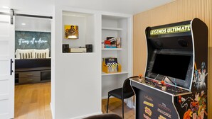 A room with a bed, a desk, a chair, and a gaming arcade. - Family Oasis! Hot Tub Fire Pit Game Room Sleeps 12 (San Diego)