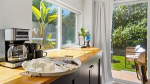 A kitchen with a coffee maker, a plate of marshmallows, and a view of a garden through large windows. - Family Oasis! Hot Tub Fire Pit Game Room Sleeps 12 (San Diego)